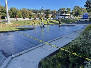 Diligent crew smoothing level asphalt parking lot